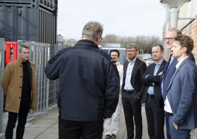 Outside the CBS1 facility, Steen B. Iversen is explaining to the visitors. Far left is the secretary to the minister and Daniele Castello, AAU, in the white protective suit. Credits: AAU